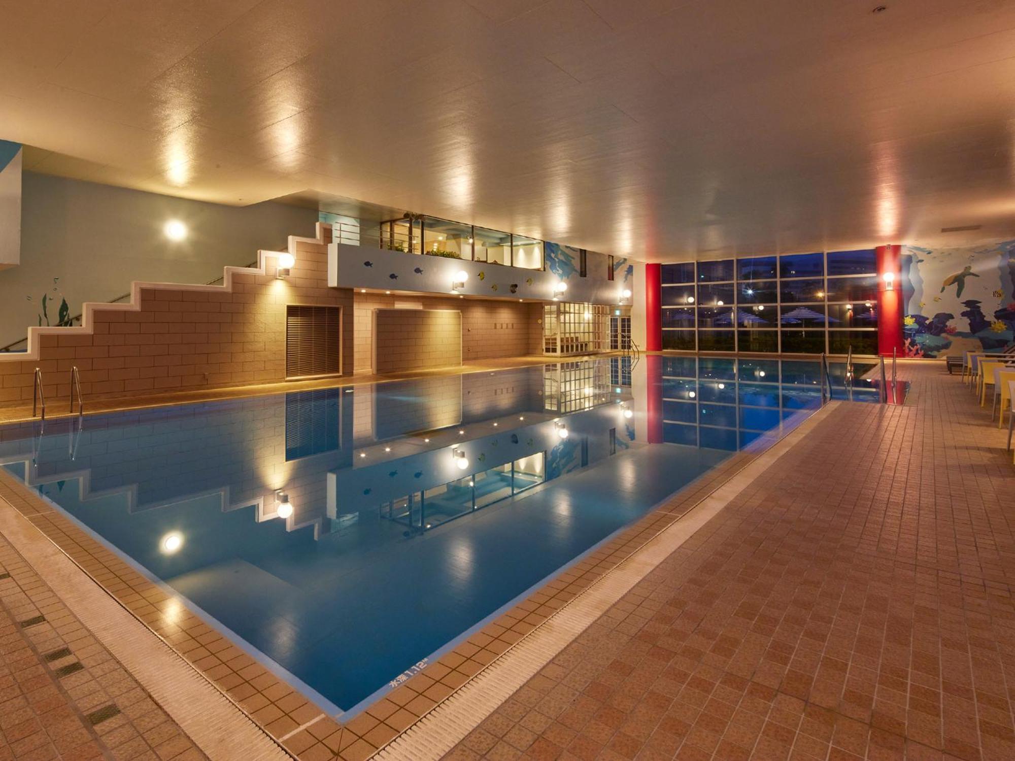 Hotel Grand Nikko Tokyo Bay Maihama Urayasu Exteriér fotografie The photo shows an indoor swimming pool area. The pool features a calm blue water surface and is surrounded by tiled flooring. There is a staircase leading to a higher level, likely providing access to a lounge or seating area. Large windows allow na